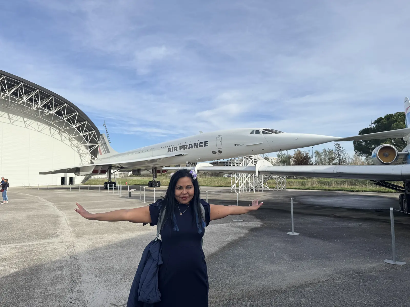Sarah standing with outstretched arms in front of an Air France Concorde in Toulouse